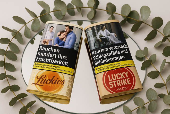 Zwei Lucky Strike Tabak Pouches auf einem Spiegel mit Eucalyptus umringt