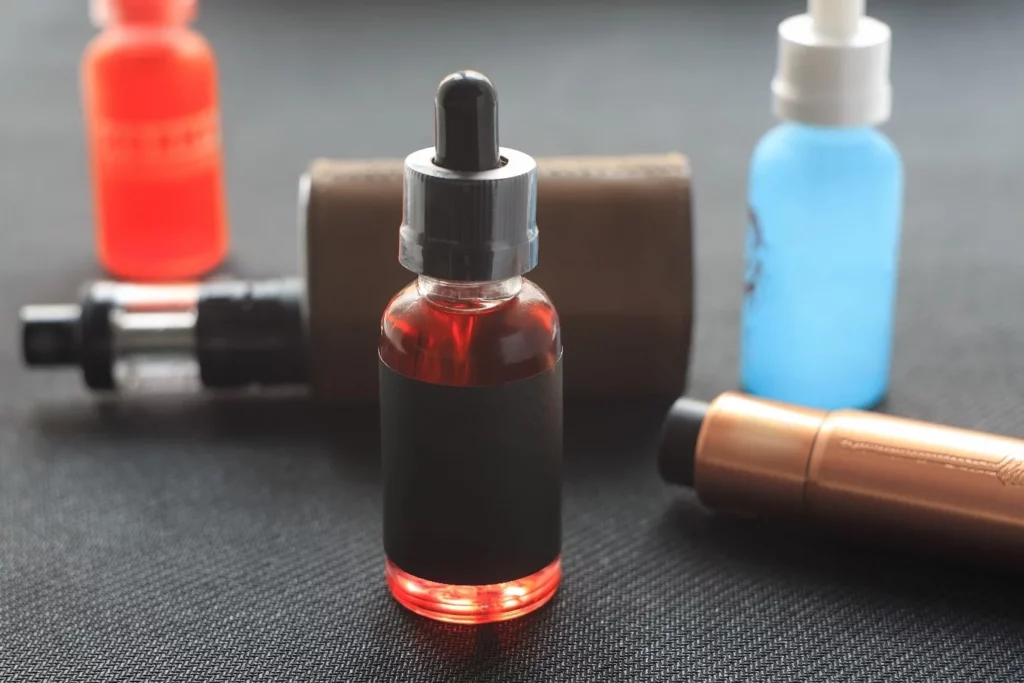Verschiedene Liquids und E-Zigarette im Hintergrund