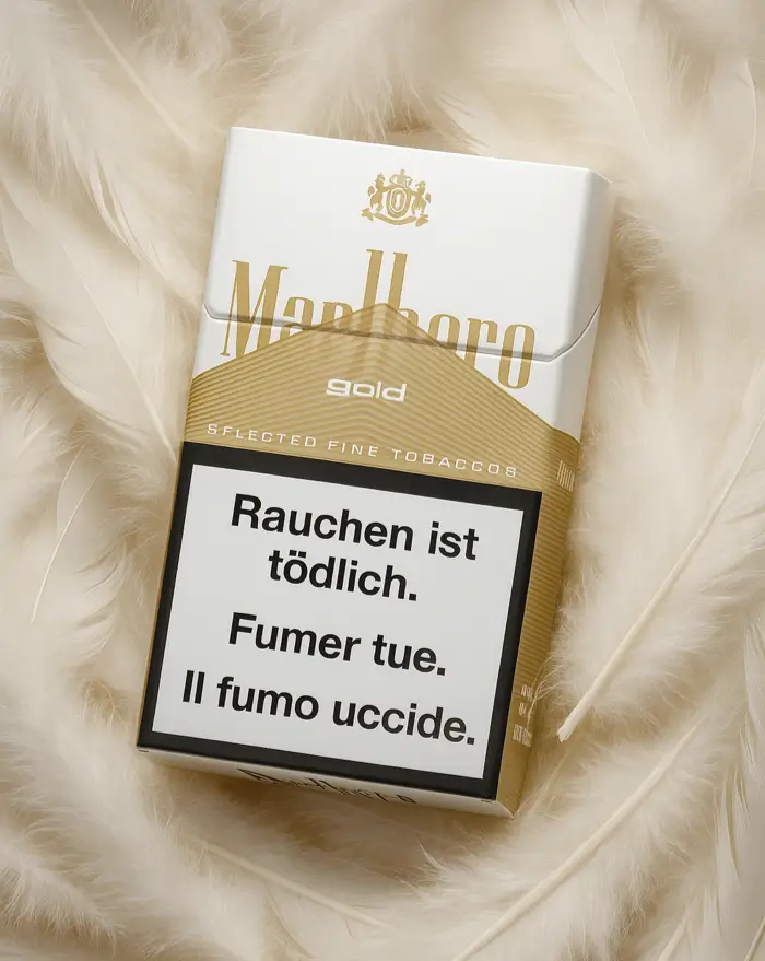 Marlboro Gold Zigarettenschachtel mit Warnhinweis „Rauchen ist tödlich“ auf weißem Hintergrund, umgeben von weichen Federn.