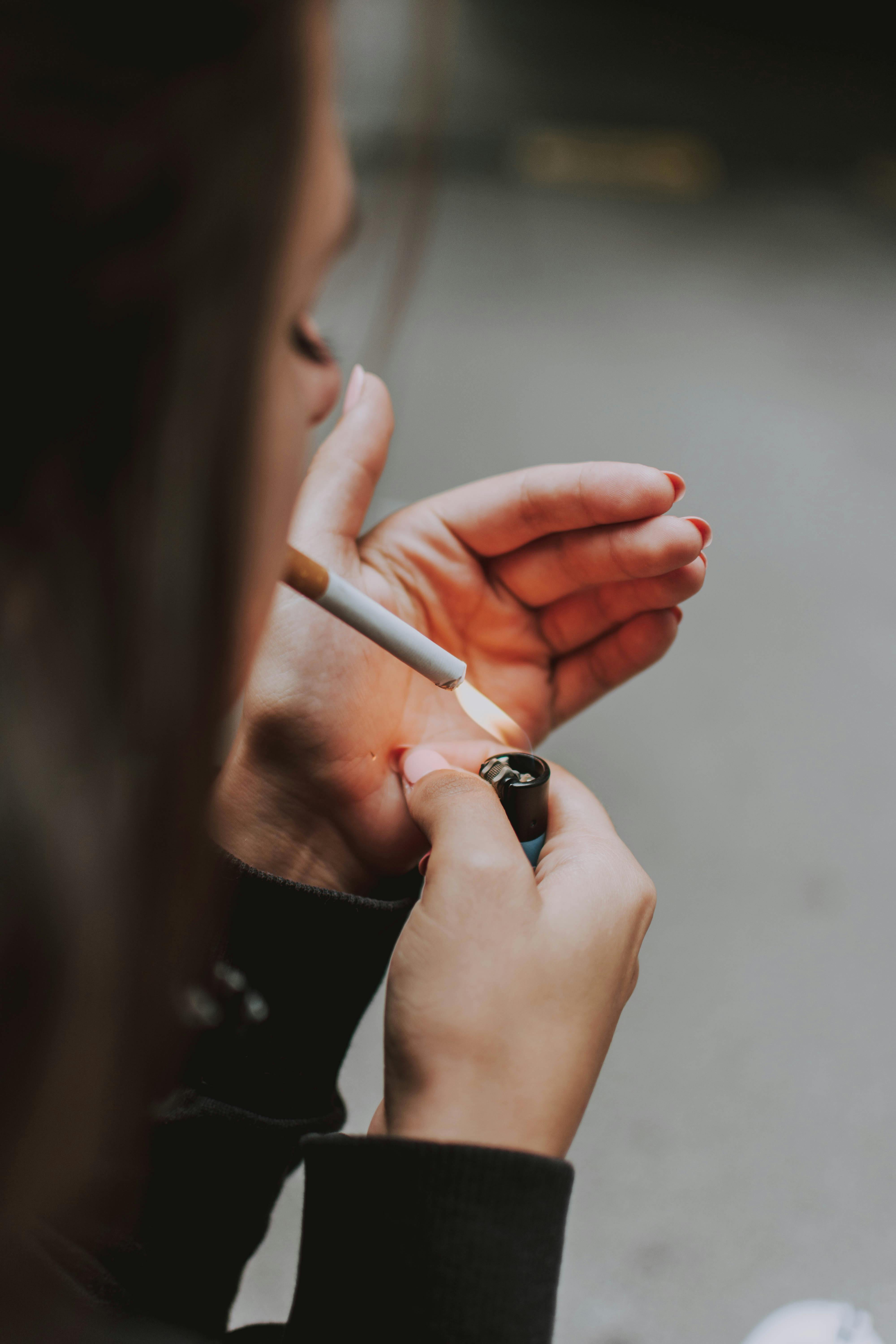 Frau die sich eine Zigarette anzündet, mit einem Feuerzeug